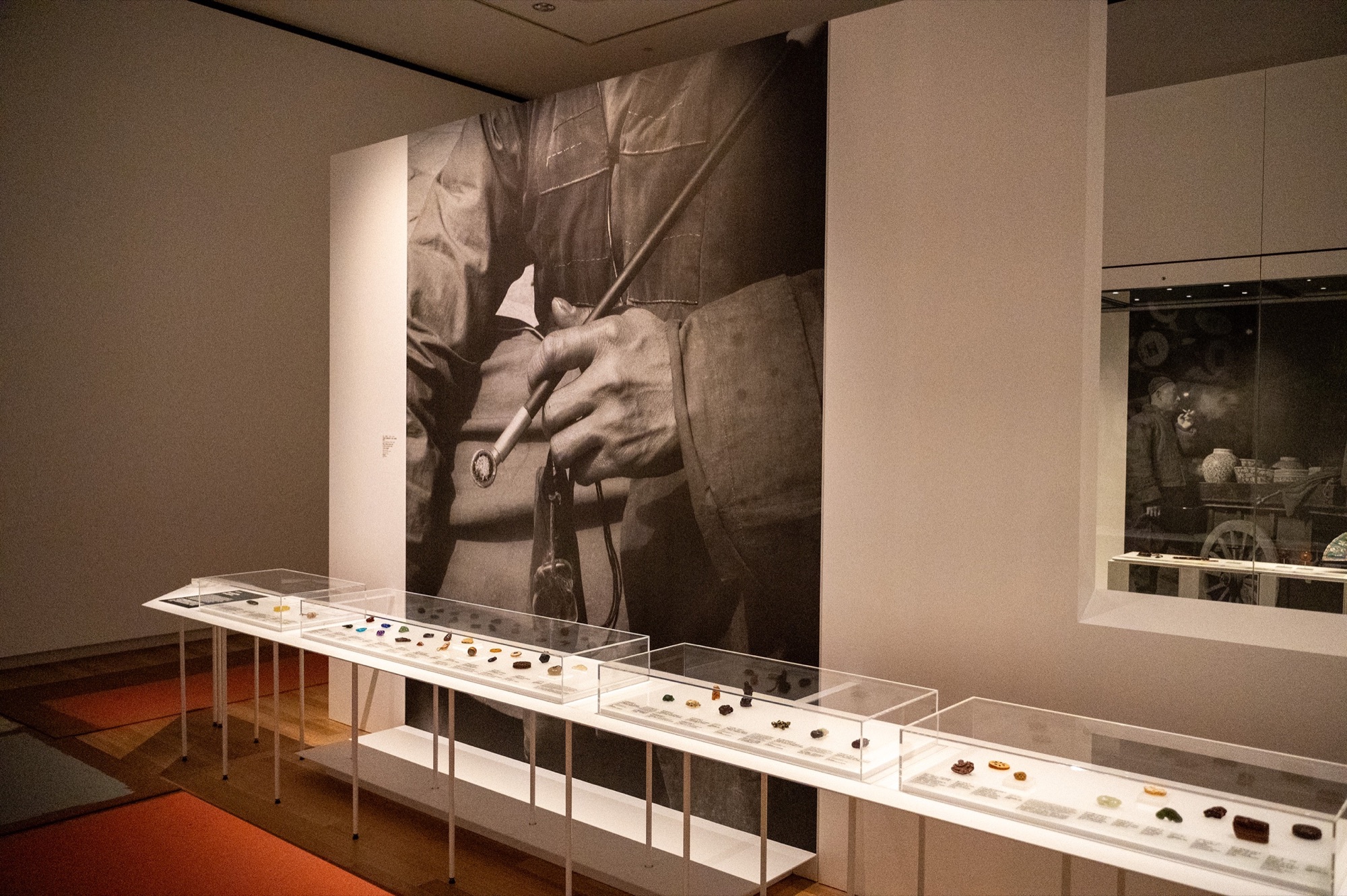 Display case of miniature Chinese toggles in front of a large photographic wall graphic.