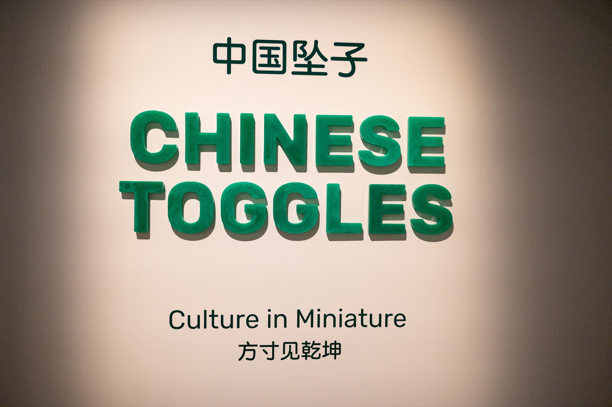 Translucent green Chinese Toggles title lettering with bilingual introduction text at Chau Chak Wing Museum.